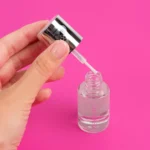 Semilac Primer Witaminowy 7 ml – otwarta buteleczka z pędzelkiem na różowym tle