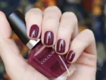 CUCCIO 1225 lakier tradycyjny 13 ml – swatch ciemnobordowy na paznokciach, dłoń trzyma butelkę Colour