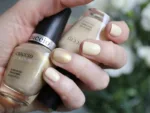 CUCIO 6419 Lakier do paznokci 13 ml – swatch beżowo-złotego lakieru na paznokciach z butelką w dłoni