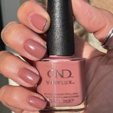 Vinylux #475 Mauve-morphosis 15 ml – dłoń z różowo-beżowym lakierem trzymająca butelkę