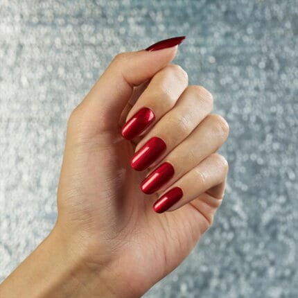 Vinylux #482 Dragon Slay All Day 15 ml. – dłoń z metaliczno-czerwonym lakierem na srebrnym brokatowym tle