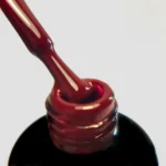 Palu lakier hybrydowy Hollywood R2 11 g – swatch ciemnoczerwonego bordo na pędzelku nad buteleczką