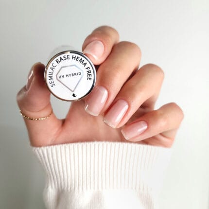 Semilac Base Hema Free 7 ml – dłoń trzymająca buteleczkę bazy, naturalne paznokcie z połyskiem, widoczna nakrętka z napisem